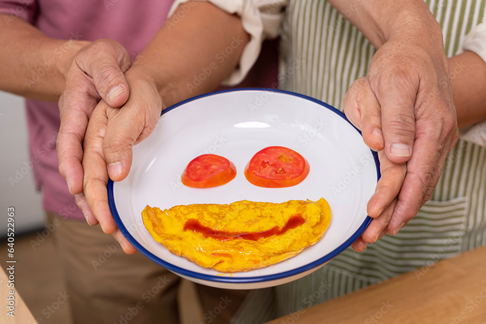 An old couple made an omelette breakfast with ketchup painted in smiles. Old man's hands intertwined. An old couple made an omelette breakfast with ketchup painted in smiles. Old man's hands intertwined.