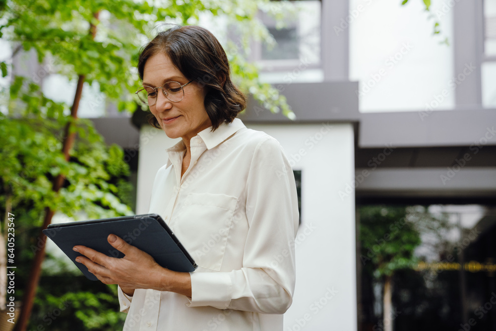 Business woman working on tablet computer while standing outdoors Business woman working on tablet computer while standing outdoors