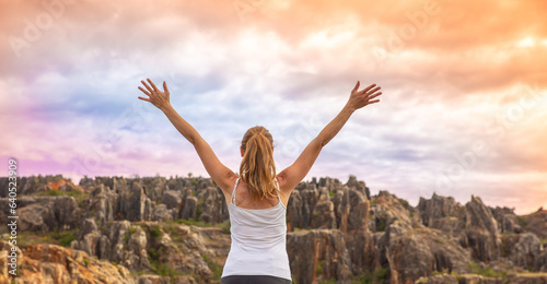 Happy woman with arms raised up in nature at sunset