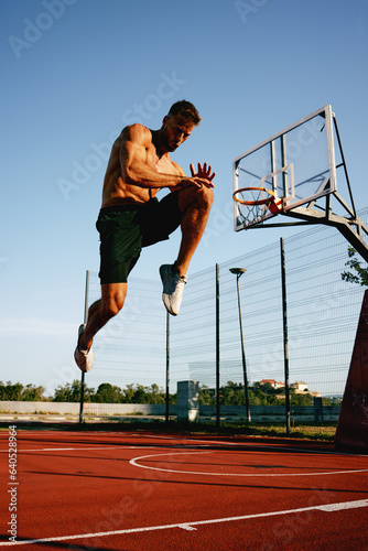 Shirtless handsome man doing jumps warm-up on the basketball court outside