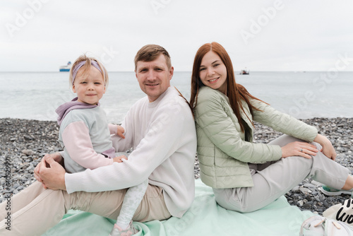 Happy family with a child of 2 years old on the seashore have a rest