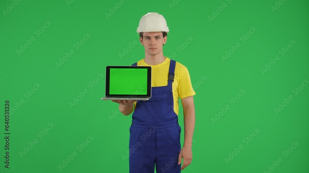 Medium green screen isolated chroma key shot of a young construction worker holding a laptop with advertising area, workspace mock up. Medium green screen isolated chroma key shot of a young construction worker holding a laptop with advertising area, workspace mock up.