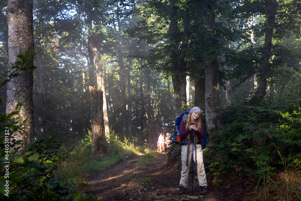 girl hiker with a backpack on a path in the forest