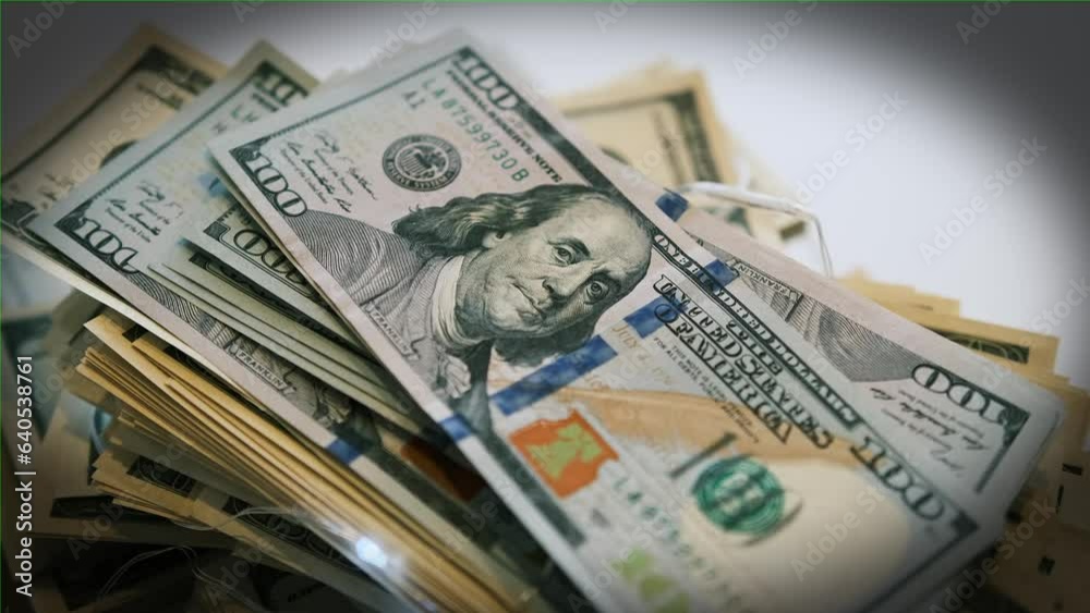Many hundred American dollars bills paper money cash macro slow motion close up, vignette. Many 100 dollar lies on white table. Idea financial success Many hundred American dollars bills paper money cash macro slow motion close up, vignette. Many 100 dollar lies on white table. Idea financial success