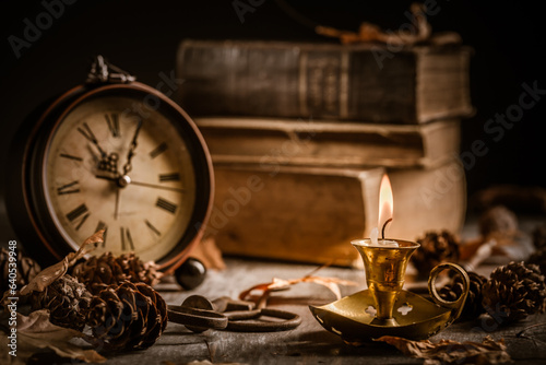 Vintage still life with antique books, clock and candle. Halloween and occult concept.