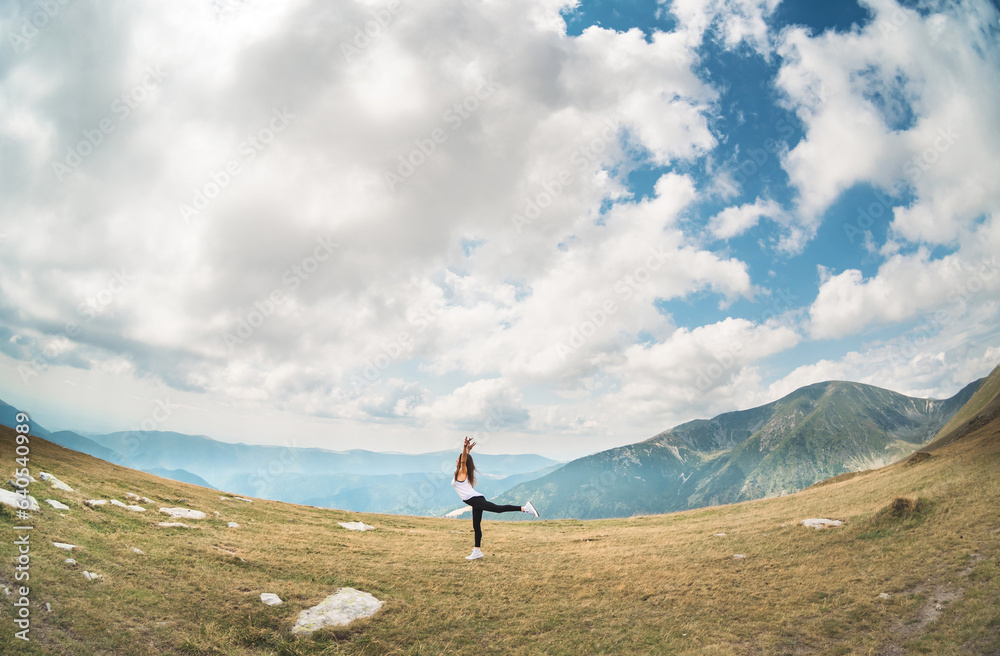 A young ballerina does gymnastics in a beautiful mountain landscape. Beautiful young woman dancing. Frame, wide angle