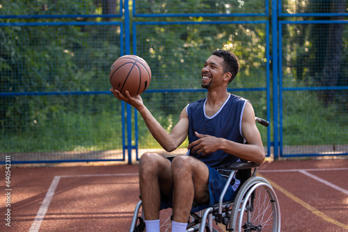 Fototapeta Naklejka Na Ścianę i Meble -  Happy basketball player with disability uses wheelchair while playing on sports court.