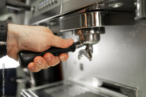 Close-up of barista inserting portafilter into coffee machine espresso making process
