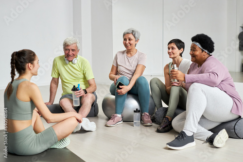 Group of elderly people drinking water and resting after training together with coach © AnnaStills