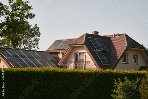 Modern black cells solar panels on the roof of private house. Photovoltaic dotation from European parliament government concept. Renewable energy for the home concept. Sustainable living future.
