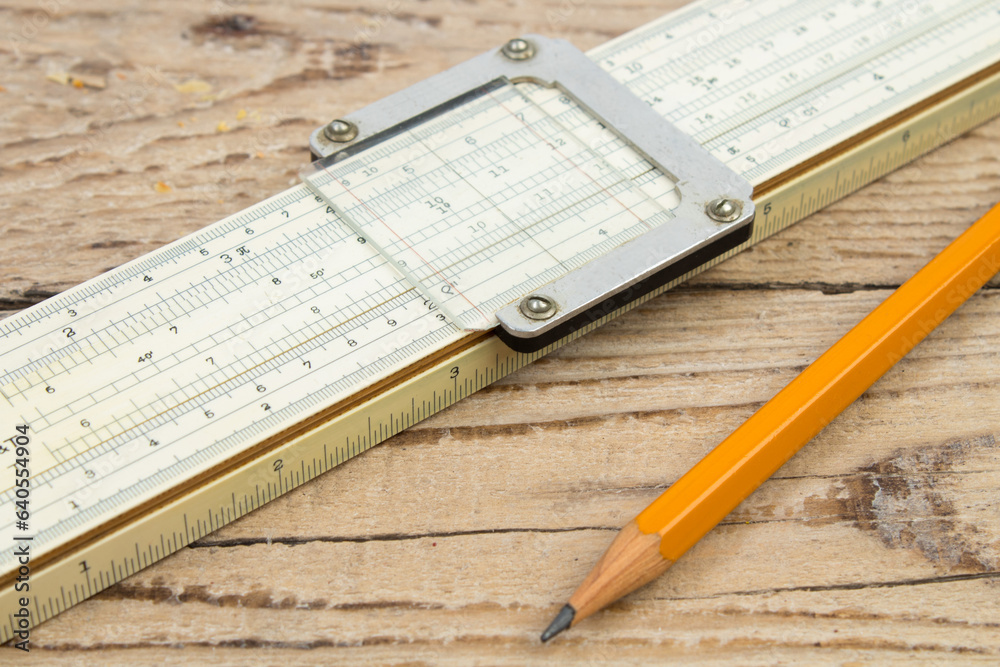 Logarithmic ruler, pencil on a wooden table. Stationery for engineers and students. Logarithmic ruler, pencil on a wooden table. Stationery for engineers and students.