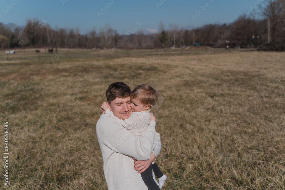 A man tightly hugs a small child in a dry field A man tightly hugs a small child in a dry field