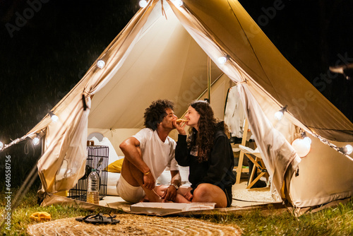 couple in love eating pizza in a camping tent