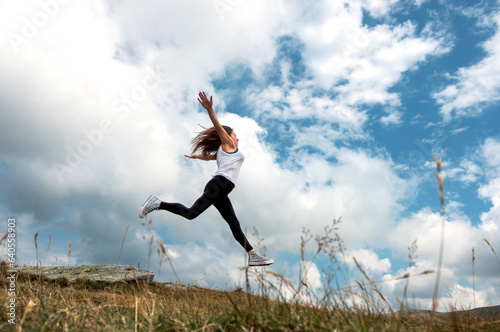 The woman jumps through the clouds. Aspirations  challenges  dreams - concept. The young woman was enjoying the beautiful scenery.