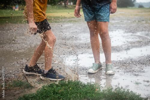 Kids splashing in mud puddle in the rain
