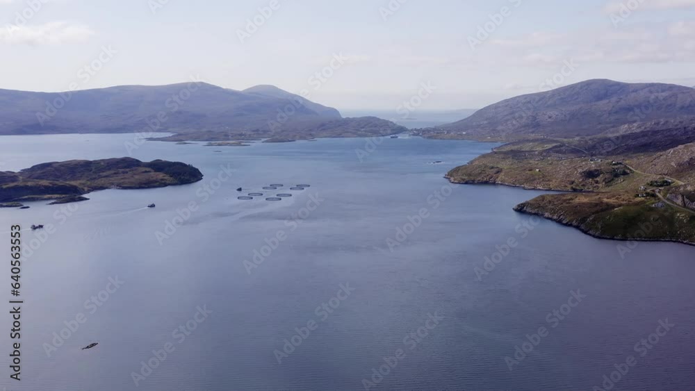 Wide drone shot of the bay around Tarbert, a village on the Isle of Harris, part of the Outer Hebrides of Scotland. A fish farming facility is visible as well as many mountains and cliffs. Wide drone shot of the bay around Tarbert, a village on the Isle of Harris, part of the Outer Hebrides of Scotland. A fish farming facility is visible as well as many mountains and cliffs.