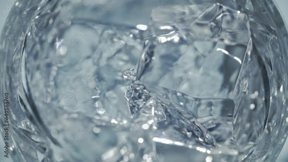 Super Slow Motion Detail Shot of Pouring Vodka on Crystal Clear Ice Cubes at 1000 fps.