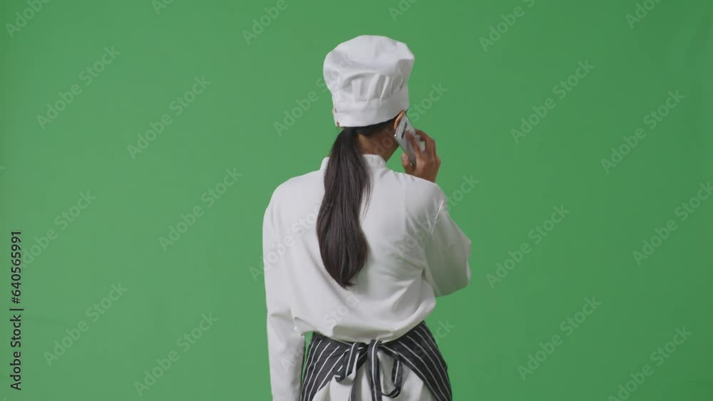 Back View Of Asian Woman Chef Talking On Smartphone While Walking In The Green Screen Background Studio
Back View Of Asian Woman Chef Talking On Smartphone While Walking In The Green Screen Background Studio
