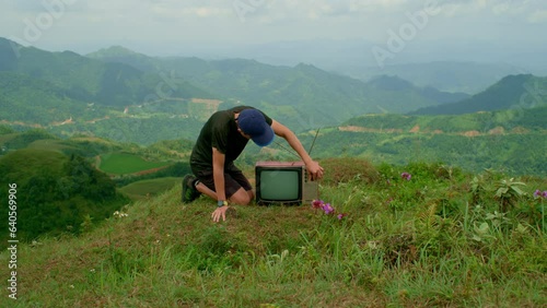 curious man inspects a television set on a mountainside photo