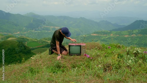 young man taps on the top of a cathode-ray tube television to get it to work after reception goes out photo