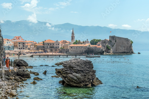Budva, Montenegro - June 17, 2021: Seascape of the coastline of the Adriatic Sea with a view of Budva Old Town and Plaza Ricardova Glava beach. Beautiful panorama of the tourist town in the Balkans photo