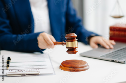 justice and law concept.law theme wooden desk, books, balance. Male judge in a courtroom the gavel,working with digital tablet computer on desk.