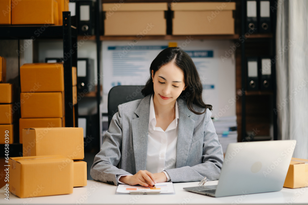 Startup small business SME, Entrepreneur owner woman using smartphone or tablet taking receive and checking online purchase shopping order to preparing pack product box. .. Startup small business SME, Entrepreneur owner woman using smartphone or tablet taking receive and checking online purchase shopping order to preparing pack product box. ..