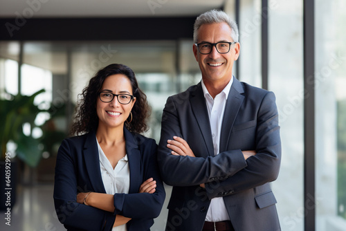 Happy confident professional mature business man and business woman corporate leaders managers standing in office, two diverse colleagues executives team posing together, portrait