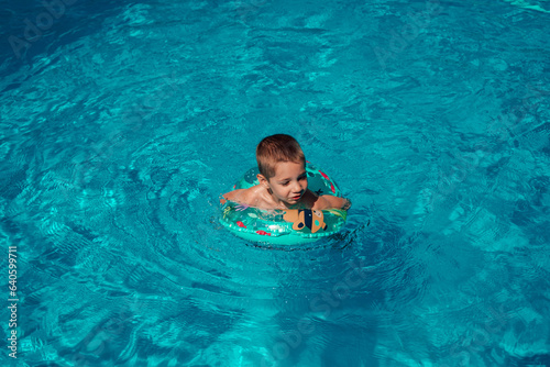 A little boy with a circle bathes in clear blue water. Swimming in the pool © Ирина Санжаровская
