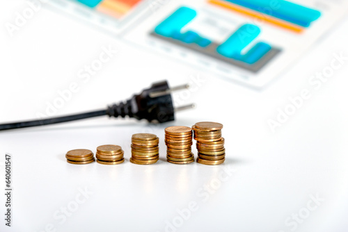 Plug of electrical device, coins and graphics. Price of electricity, crisis, inflation