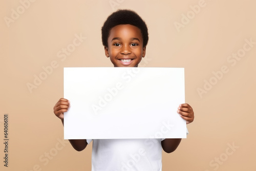 Happy black scholl boy holding blank white banner sign, isolated studio portrait. photo