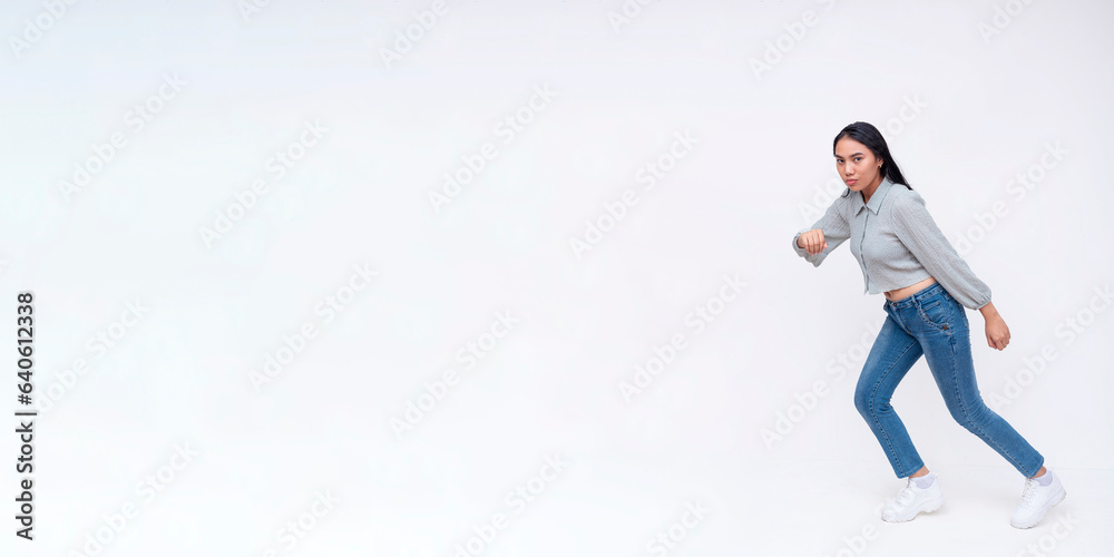Side view of a dynamic young asian woman running to the left. Wearing casual clothing going at a fast pace. Copy space on the left. Isolated on a white background. Side view of a dynamic young asian woman running to the left. Wearing casual clothing going at a fast pace. Copy space on the left. Isolated on a white background.