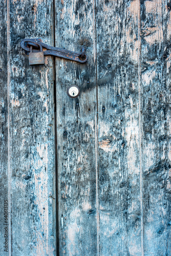 A close up of a lock and padlock on an old weathered door, cool tones, vertical