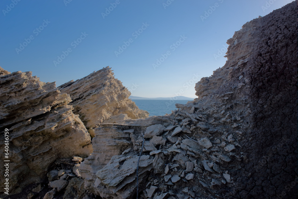 Texture of layers of limestone rock formations overlooking the sea and blue sky