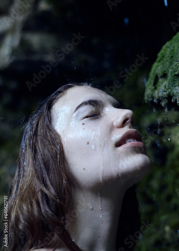 portrait of a beautiful woman under raindrops standing in the forest enjoying nature