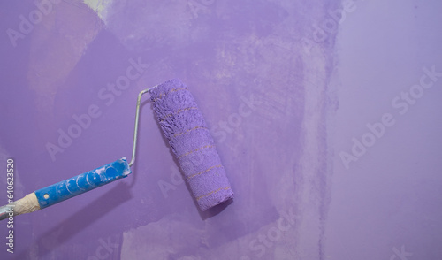 Using a paint roller to paint a concrete wall inside a house with water-based paint