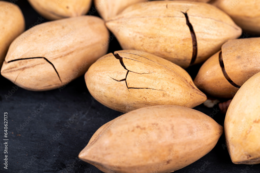 Obraz premium cracked unpeeled pecans close-up on the table