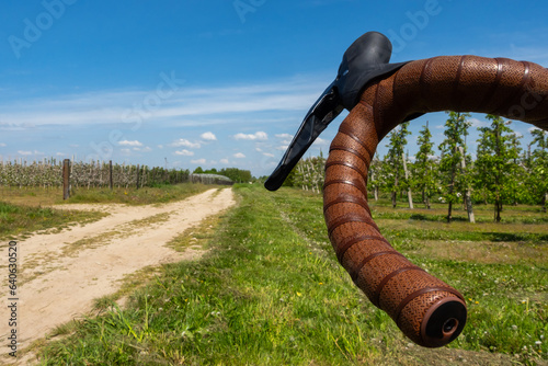 фотографія The lower handlebar grip of a gravel bike against the background of a dirt, sandy road