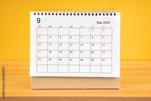 The September 2023, Monthly desk calendar for 2023 year on wooden table with yellow background.