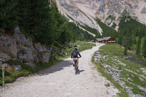 Tourist riding his Electric Mountain Bicycle on a Mountain Dirt Road in A Route Of The Alps, Italy photo