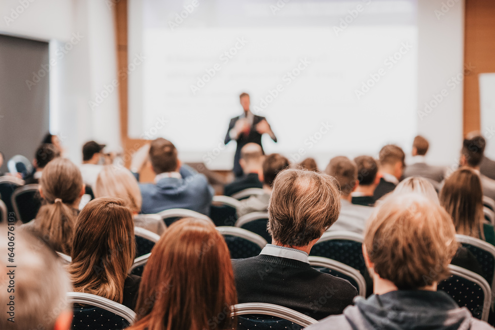 Speaker giving a talk in conference hall at business event. Rear view of unrecognizable people in audience at the conference hall. Business and entrepreneurship concept