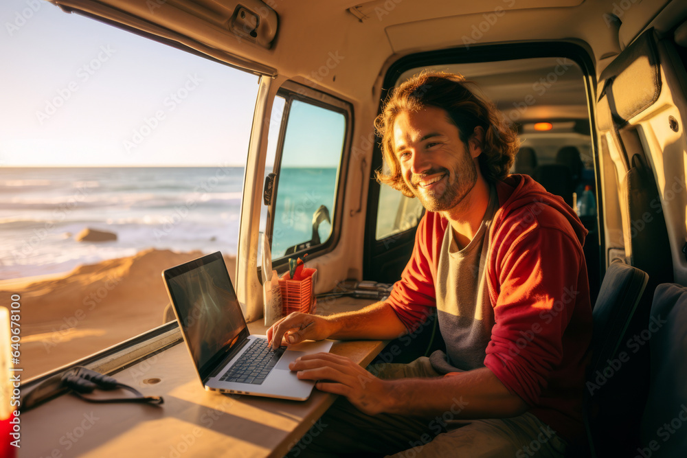 Fototapeta premium Handsome young digital nomad using a laptop computer in camper van on sunny day. Man working remotely with his laptop. Digital nomadic life.