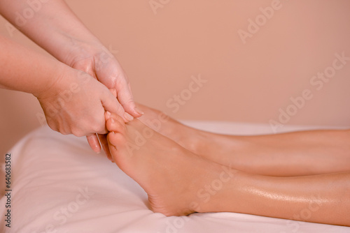 Professional foot massage close up. Authentic shot of spa treatment. Place for text on beige background