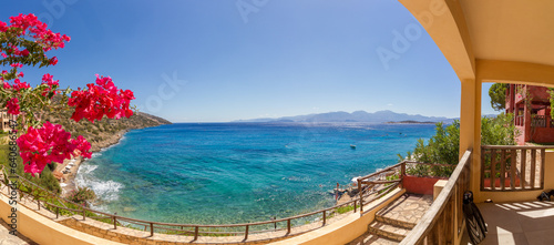 Panoramic view of the turquoise mediterranean sea at the island of Crete, Greece, near Agios Nikolaos, with pink bougainville flowers and fins
