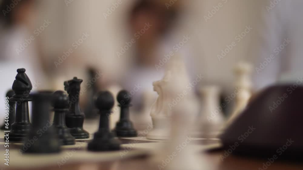 Close-up of a Hand Moving a Chess Piece on the Board. Chess Tournament. Hands, people and chess board game in closeup. Close-up of a Hand Moving a Chess Piece on the Board. Chess Tournament. Hands, people and chess board game in closeup.