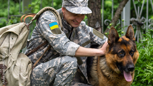 A Ukrainian soldier in military uniform with dog, yellow and blue flag.