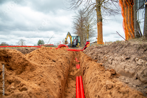 Network cables in red corrugated pipe are buried underground on the street. underground electric cable infrastructure installation. photo