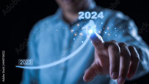Businessman hand drawing line for increasing arrow from 2023 to 2024 for preparation new year