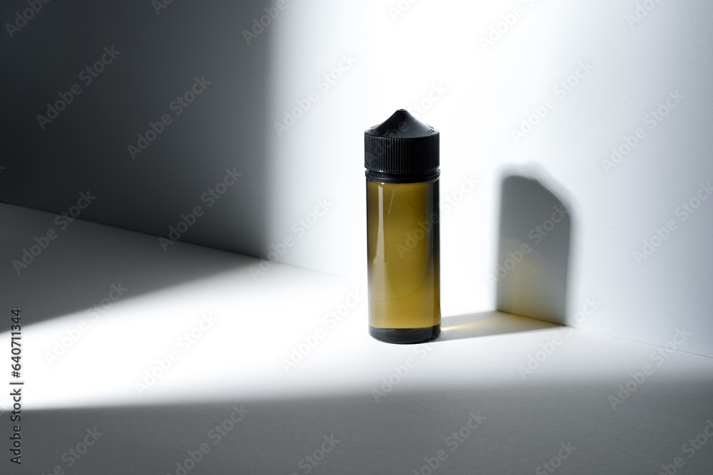 Dropper bottle with vape liquid on white background in the sunlight with shadows Dropper bottle with vape liquid on white background in the sunlight with shadows