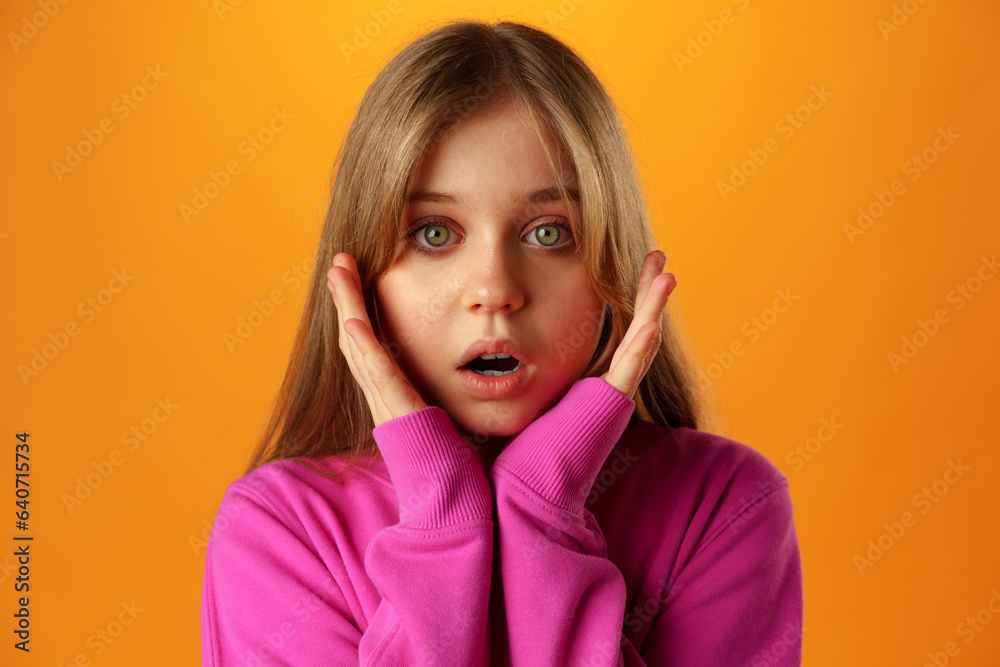 Surprised teenage girl over yellow background in studio Surprised teenage girl over yellow background in studio